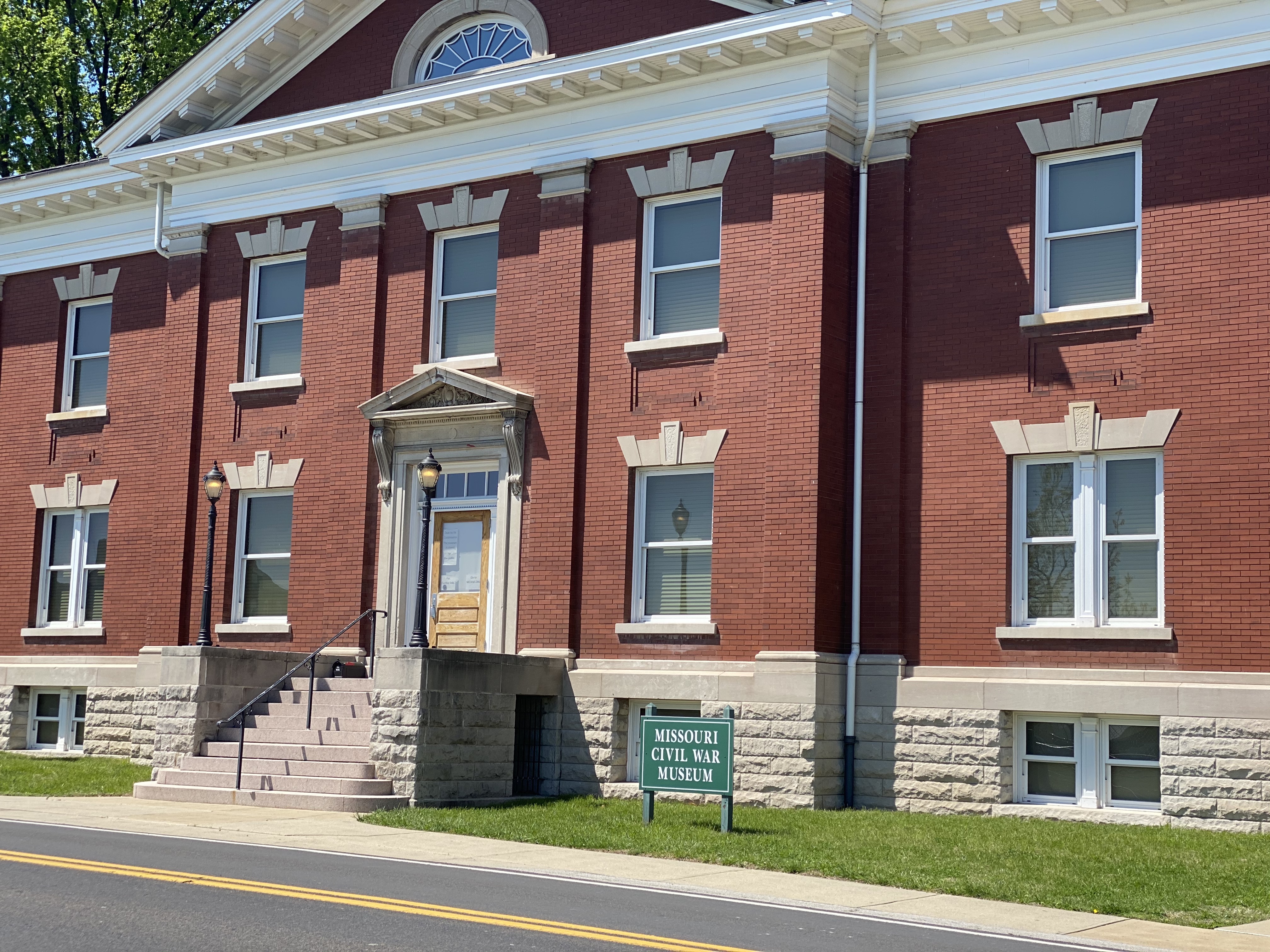 The Missouri Civil War Museum has a brick exterior with various windows in the front of the building. There are steps leading to the front door with a black railing.