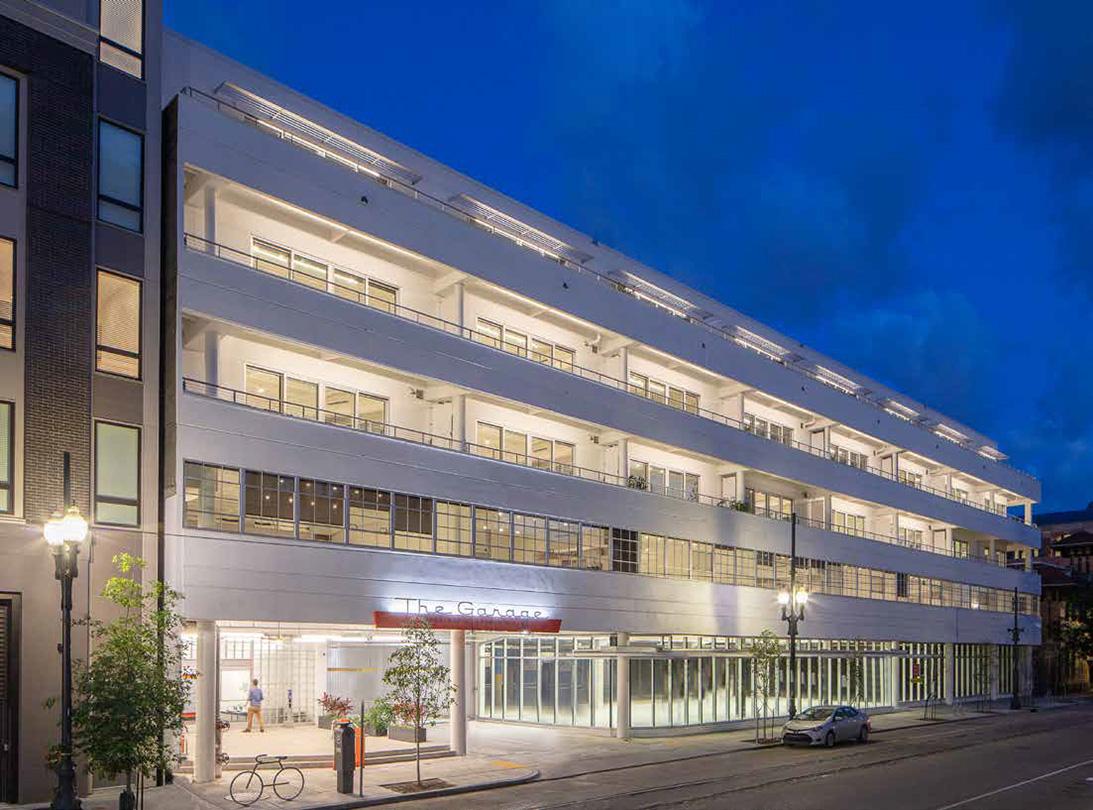 Stephens Garage, a luxury apartment building converted from an old garage, is lit up at night, with large rolling doors on the bottom floor and steel replica windows installed side-by-side all along the upper floors.