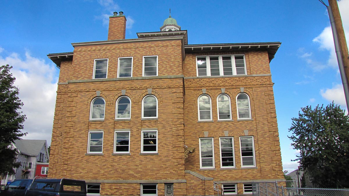 Beige brick building with aluminium windows and car in front of building
