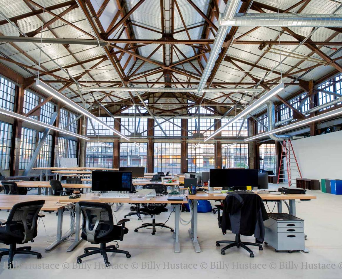 A large indoor room featuring a desk with chairs, with natural daylight illuminating the space.