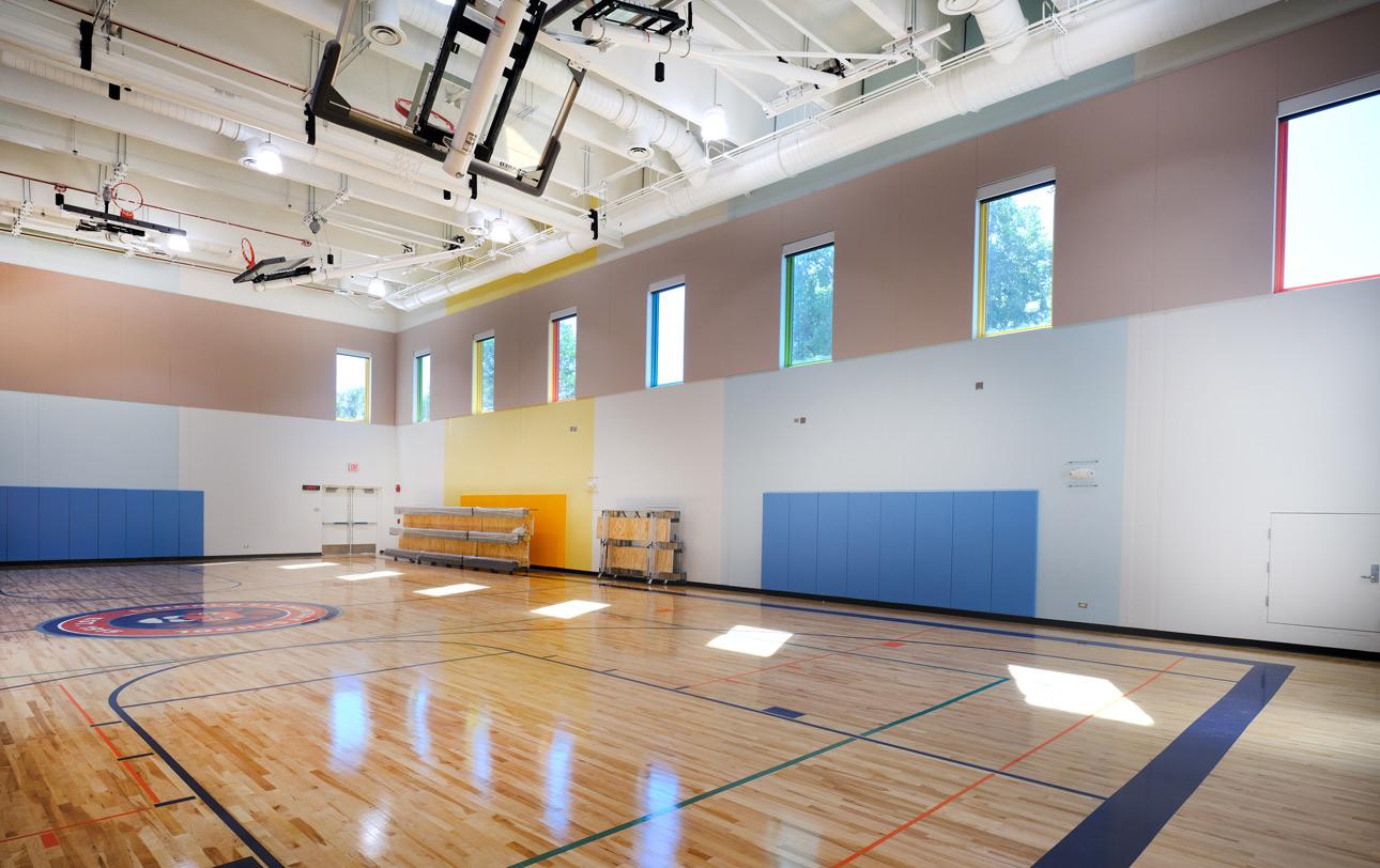 A large interior gym with tornado resistant windows against a clear blue sky, showcasing a school’s safe room.