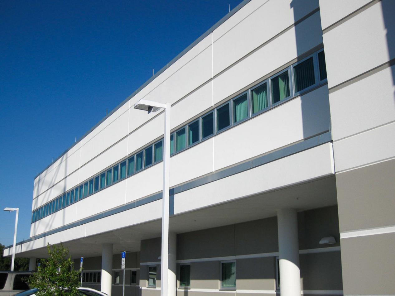 A tall commercial building with numerous windows against a clear blue sky. The architectural facade showcases a modern design, emphasizing the glass and structure of the property.