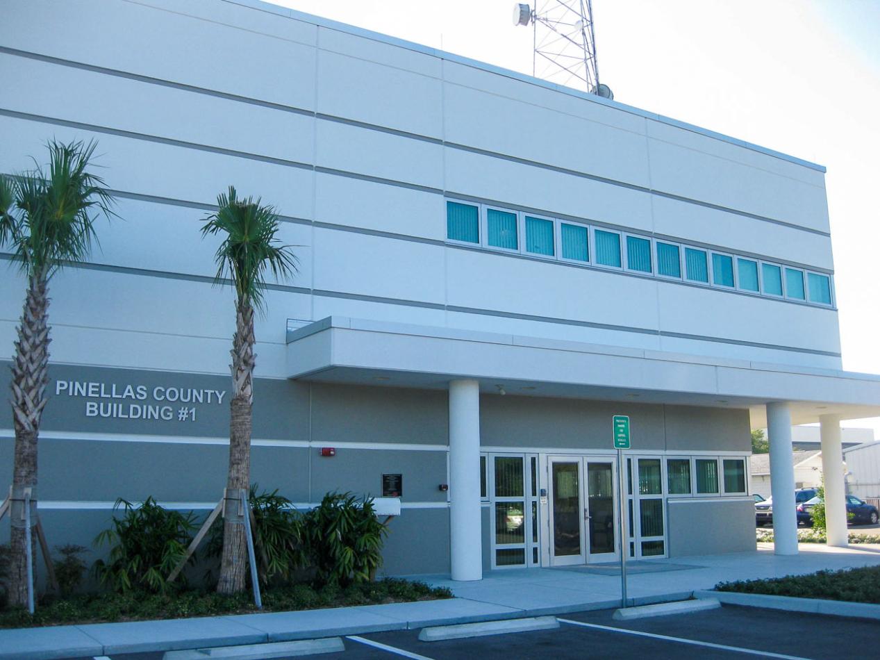 A tall commercial building with numerous windows against a clear blue sky. The architectural facade showcases a modern design, emphasizing the glass and structure of the property.