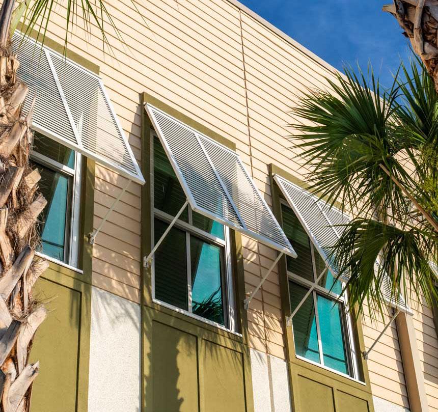 Close up of single hung windows at school building at dusk with palm trees in front.
