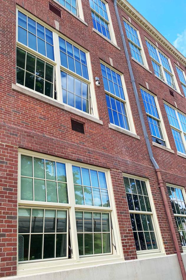 A brick building featuring a window, showcasing red brickwork and sky in background..