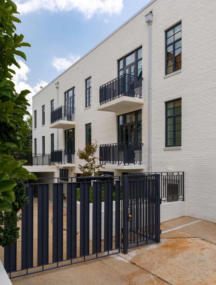 A white brick building featuring black metal gates and balconies, showcasing WINCO’s NC82 Terrace Doors for hurricane safety