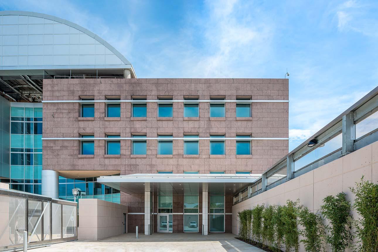 Main entrance of a hospital featuring stone architecture and Human Impact Resistant Windows for patient care rooms.