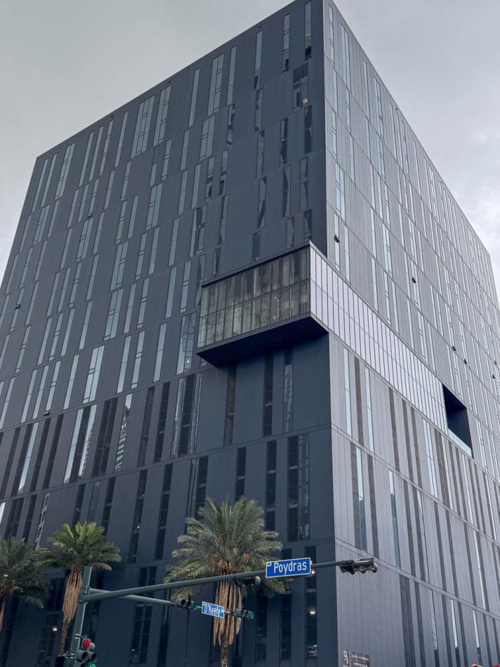 A modern building in New Orleans showcasing a random pattern of tinted windows in blue frames against gray steel panels.